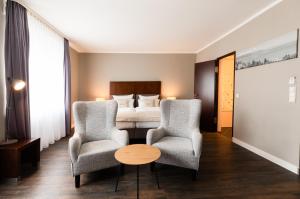 腓特烈港Select Hotel Friedrichshafen的酒店客房带两把椅子和一张床