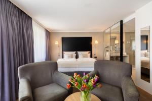 腓特烈港Select Hotel Friedrichshafen的酒店客房带两把椅子和一张床