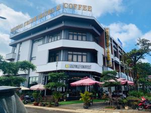 波来古市Phương Trinh Hotel & Coffee的前面有一把伞的白色大建筑