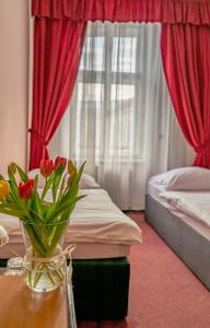 赫拉尼采Hotel Růžek的一间卧室设有两张床,一张桌子上放着花瓶