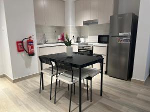 阿布扎比Partial Canal View 1br Apartment Yas Island的厨房配有黑色桌椅和冰箱。