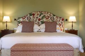 基安蒂盖奥勒卡潘尼尔葡萄酒度假酒店的一张大床,配有一个大床头板和两盏灯