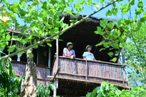 PadakaluHarakoppa Hills的两个女人在树屋的阳台上