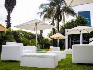 SandtonMonte La Vue Hotel的一群白色的长沙发和雨伞在草地上