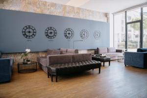 索非亚Impresamente Art Hotel的客厅配有沙发、椅子和墙上的时钟