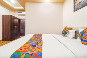 NaksalbāriFabHotel Roadside Inn的卧室配有白色的床和色彩缤纷的毯子