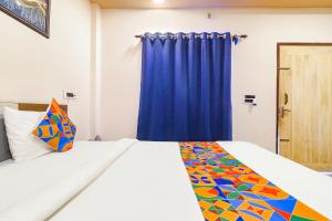 NaksalbāriFabHotel Roadside Inn的一间卧室配有一张蓝色窗帘的床