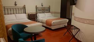 波托西Hostal Colonial Potosi的客房设有两张床、椅子和桌子。