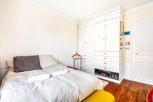 巴黎GuestReady - Estadia maravilhosa perto do Père-Lachaise的白色卧室配有一张床和黄色的搁脚凳
