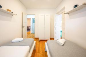 里斯本GuestReady - A lovely city refuge near Jerónimos的卧室设有两张床,拥有白色的墙壁和木地板