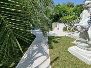 圣雷莫Palms Luxury Suites Sanremo的种有棕榈树和白色雕像的花园