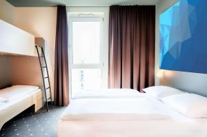 维也纳B&B HOTEL Wien-St-Marx的酒店客房设有两张床和大窗户。