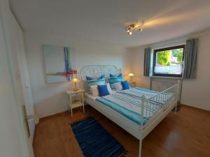 灿特Ferienhaus-Zandt的一间卧室配有一张带蓝色枕头的床和一扇窗户。