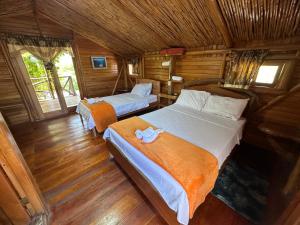 Puerto Velasco IbarraEl Pajas的木制客房内的一间卧室配有两张床
