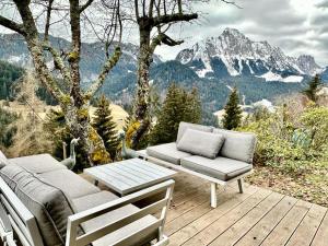 RougemontGstaad Paradise View Chalet with Jacuzzi的木制甲板配有沙发和桌椅