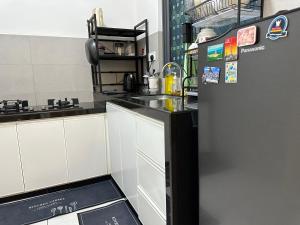 北赖Holiday Inn Stay 3B2R Meritus Residensi Perai的厨房配有白色橱柜和黑色冰箱。