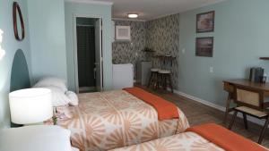 卡罗来纳比奇The Savannah Inn的一间卧室配有两张床、一张桌子和一张书桌