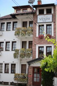 普里兹伦Hotel Venisi的白色的建筑,有很多窗户和植物