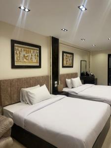 开罗Crowne Pyramids view inn的配有白色床单的酒店客房内的两张床