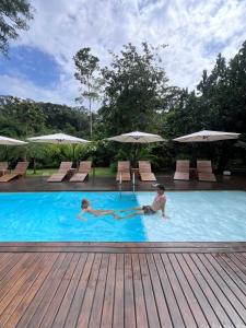 别霍港Namu Garden Hotel & Spa的2名儿童在带遮阳伞的游泳池游泳