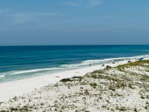 彭萨科拉海滩Pensacola Beach Front Emerald Waters的沙滩上的人在沙滩上和大海上散步