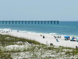 彭萨科拉海滩Pensacola Beach Front Emerald Waters的一群人在海滩上,有一个码头