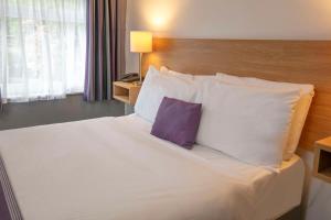 托基Tor Park Hotel, Sure Hotel Collection by Best Western的一间卧室配有一张大床和紫色枕头