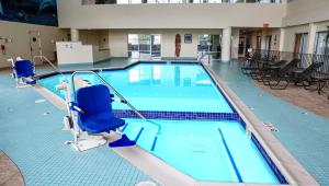 弗林特Gateway Hotel & Convention Center Grand Blanc Flint Airport Michigan的一座蓝色海水和椅子的大型游泳池