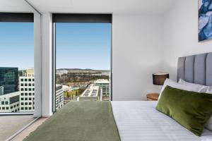 堪培拉Central Canberra 2-Bed with Gym & BBQ Area的一间卧室设有一张床和一个大窗户