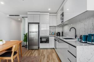 堪培拉Central Canberra 2-Bed with Gym & BBQ Area的厨房配有白色家电和木桌