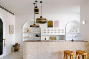 拜伦湾Basq House的厨房设有白色的墙壁和带凳子的台面
