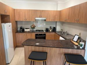 布里斯班South Brisbane 2-Bed with Views & Parking的厨房配有木制橱柜和带2把椅子的柜台。
