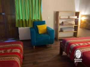 乌鲁班巴MAMA GREEN Veggie Hostal & Permaculture Farm的一张蓝色椅子和黄色枕头,位于带两张床的房间