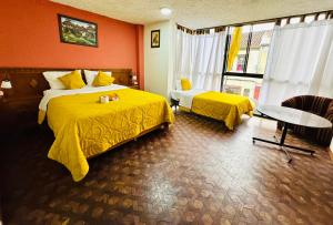 昆卡Hotel Las Americas的酒店客房设有两张床和一张桌子。