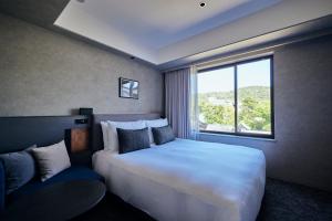 京都NOHGA HOTEL KIYOMIZU KYOTO的卧室设有一张白色大床和一扇窗户。