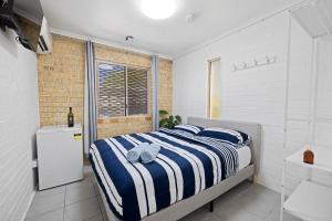 卡伦德拉Motel Sunshine Coast的一间卧室配有一张蓝色和白色条纹的床