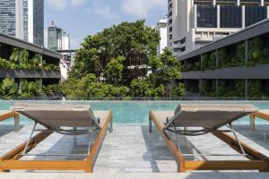 曼谷Ad Lib Hotel Bangkok的一座游泳池旁设有两把躺椅