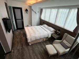 台北RF富裕自由旅店 - 林森馆的卧室配有床、椅子和窗户。