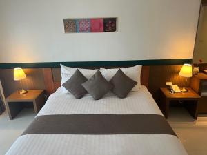 清盛暹罗三角酒店的卧室配有带枕头和两盏灯的白色床。