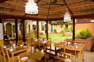 班加罗尔卡萨小屋酒店的一间带木桌和椅子的餐厅以及一个凉亭