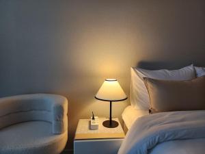 大邱동성로 Residence Daon的一间卧室配有一张床、一盏灯和一把椅子