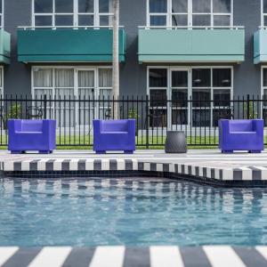 奥克兰奥克兰机场那欧米酒店的一个带蓝色躺椅的游泳池,靠近围栏