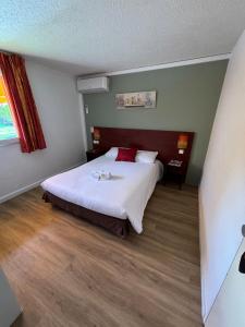 索恩河畔自由城Initial by Balladins Lyon Villefranche-sur-Saône的一间卧室配有一张大床,配有白色床单和红色枕头