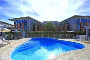 图卢兹Appart'City Confort Toulouse Purpan的大楼前的大型蓝色游泳池