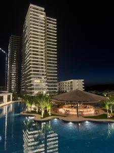 IskeleGrand Sapphire Resort 1 Bedroom Apartment的一座大型游泳池,晚上有一座高大的建筑