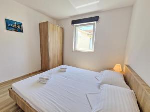 巴斯卡Apartment Pavlakovic的一间卧室配有一张带白色床单的床和一扇窗户。