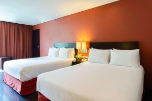 普埃布拉NH普埃布拉历史中心酒店的红色墙壁的酒店客房内的两张床