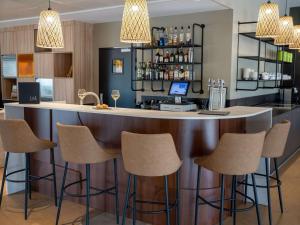 阿普瓦尼Mercure Auxerre Autoroute du Soleil的厨房里设有酒吧,配有椅子和柜台