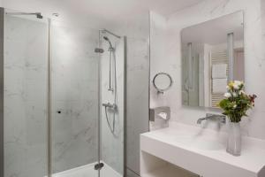 巴黎NH Paris Champs-Elysées的带淋浴、盥洗盆和镜子的浴室