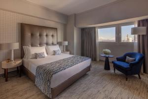 里斯本Tivoli Oriente Lisboa Hotel的一间卧室配有一张大床和一张蓝色椅子